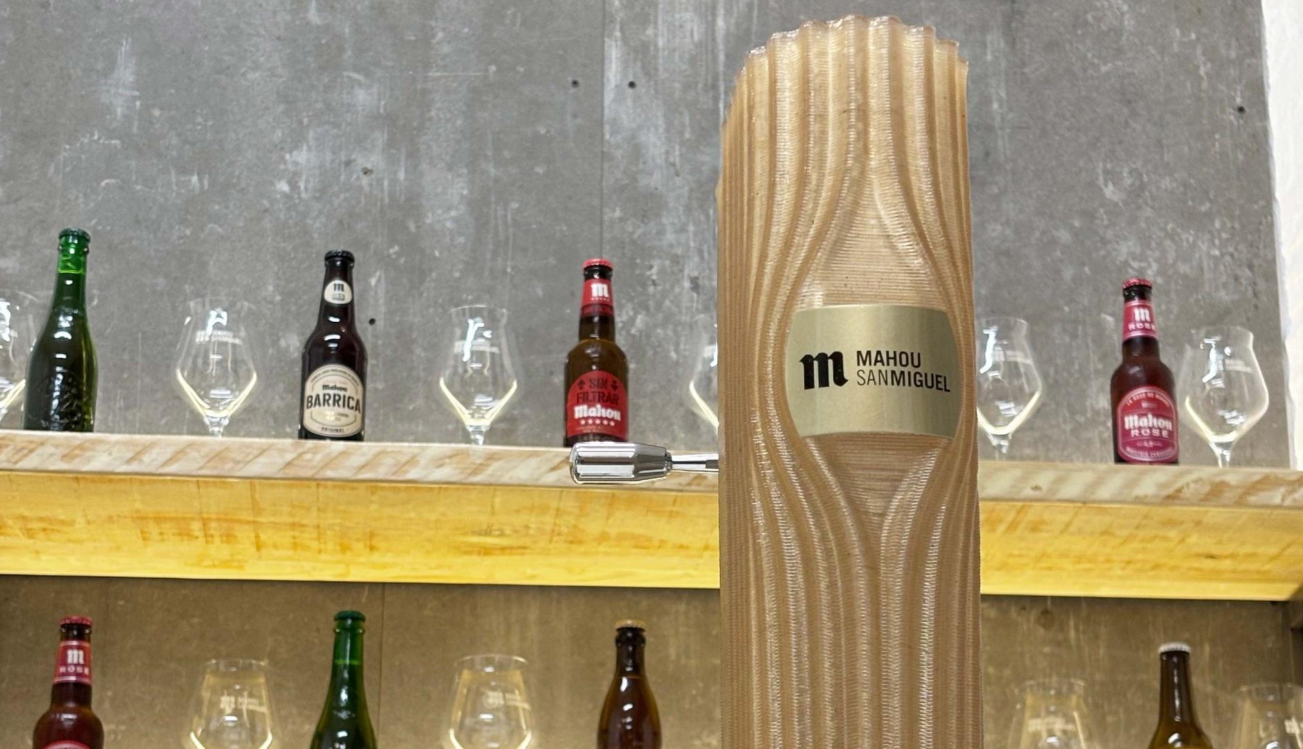 Grifo de cerveza Mahou en una barra con otros botellines en una pared e fondo