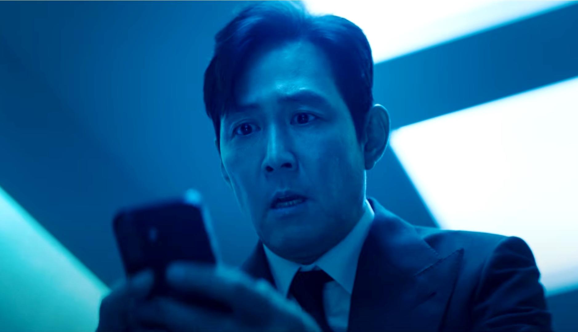 El actor Lee Jung-jae de "El juego del calamar" sujetando un móvil con cara de preocupación