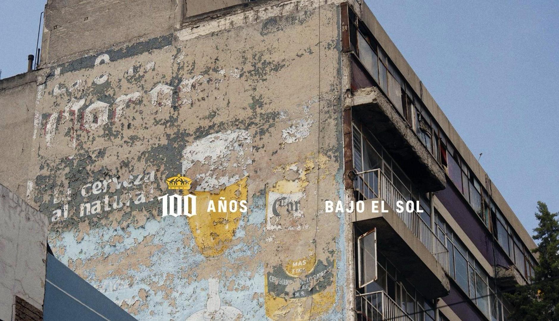 Fachada de edificio desgastada por el sol, con un anuncio de Coron