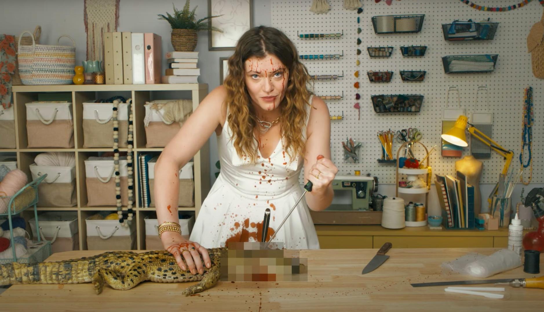 Mujer jóven clavando un cuchillo en la cabeza de un cocodrilo para enseñar a hacer un bolso birkin en la nueva campaña de PETA