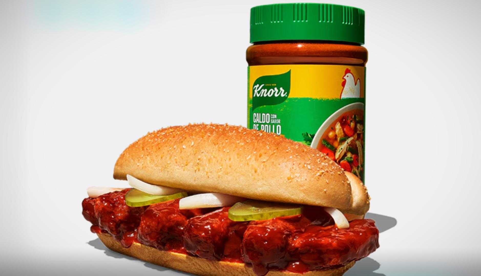 El chef Joshua Weissman y el creador de contenido gastronómico Kevin Novarpar en una cocina preparando un sándwich de costillas con la salsa Knorr.