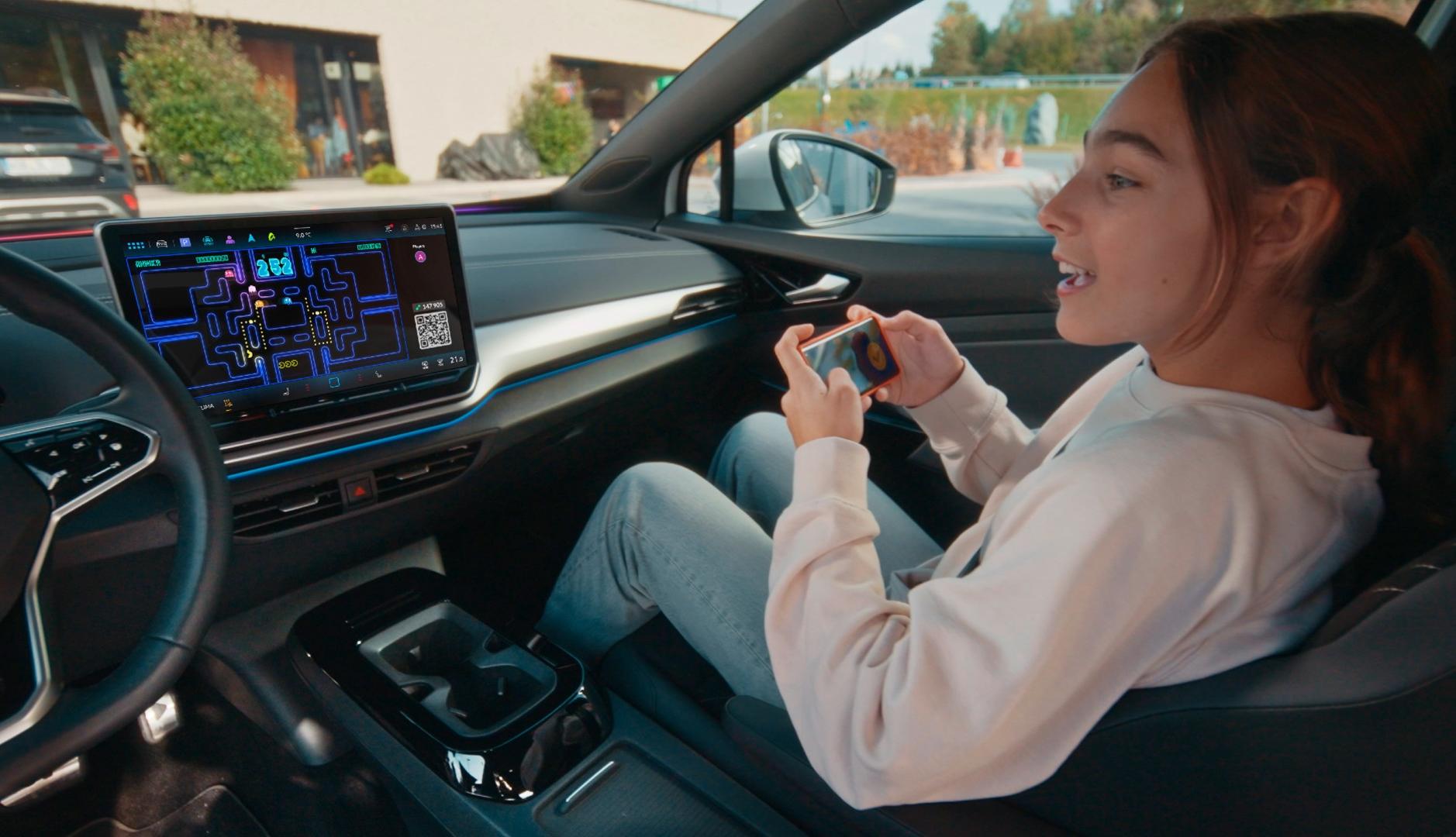 Una joven jugando a Pac-Man con el móvil desde el asiento de copiloto de un coche Volkswagen
