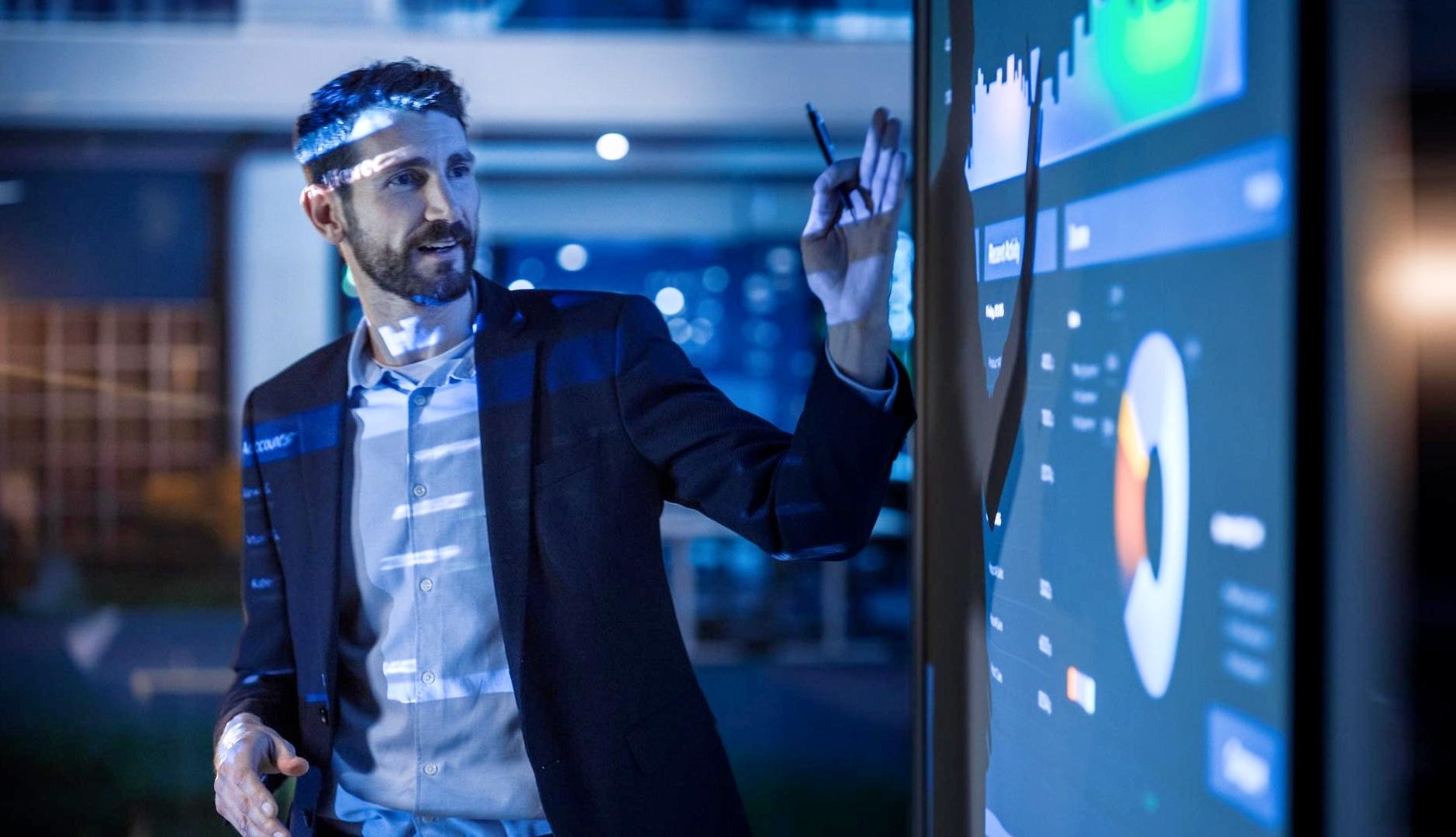 Un hombre mostrando datos y graficos en una pantalla difgital