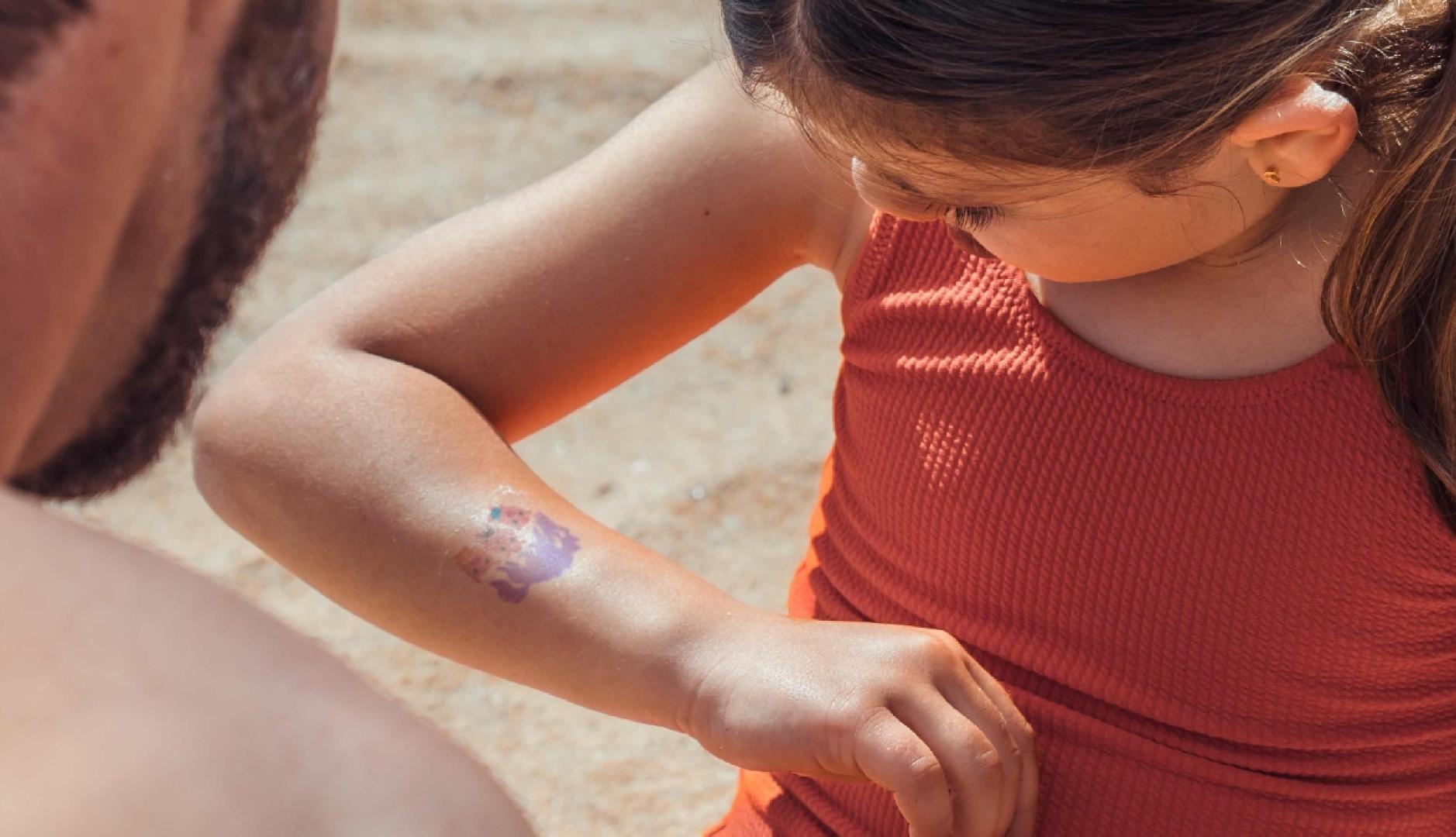 una niña mirándose el brazo con la calcomanía