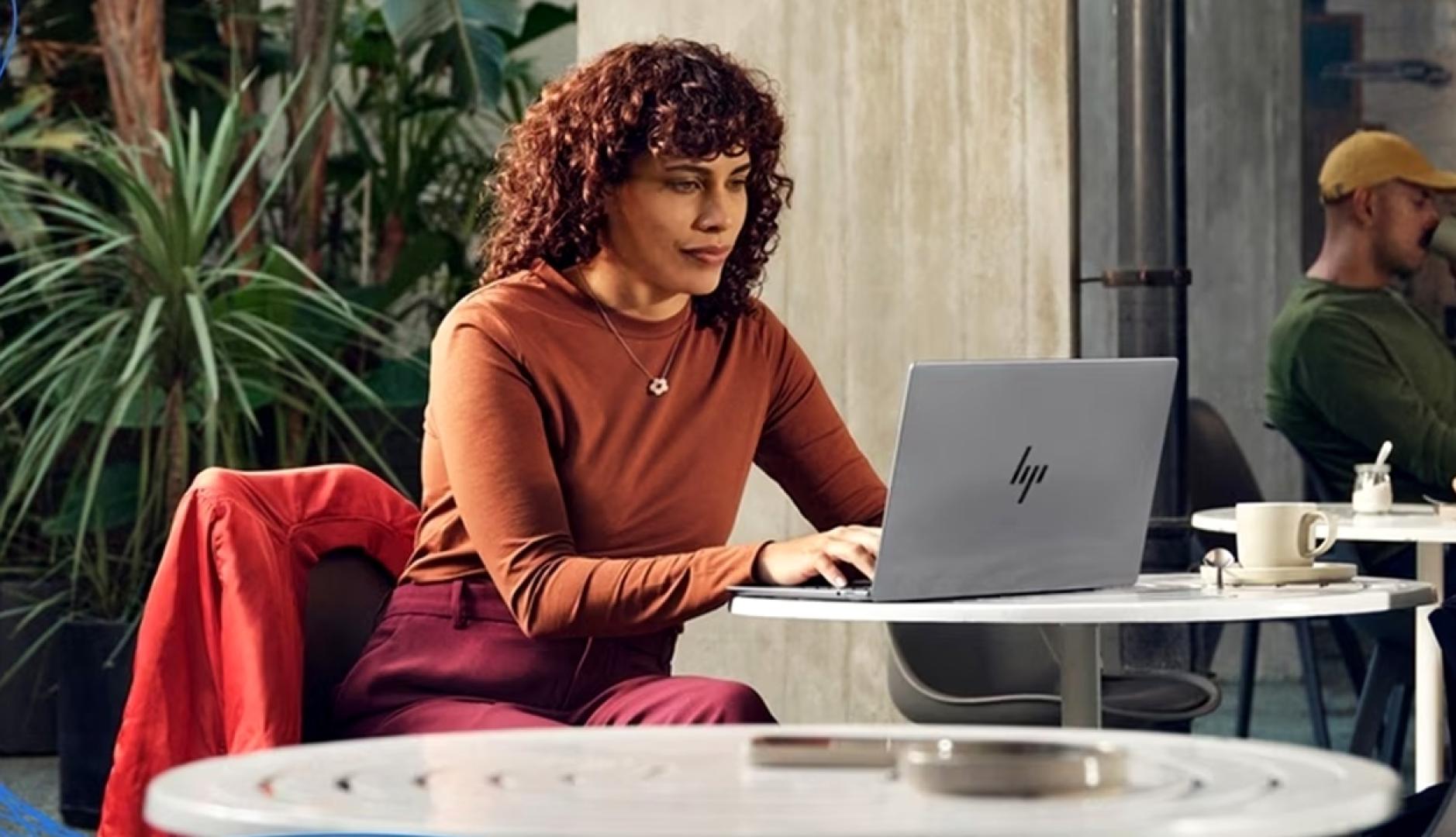 una mujer trabajando en una cafeteria con su ordenador portatil