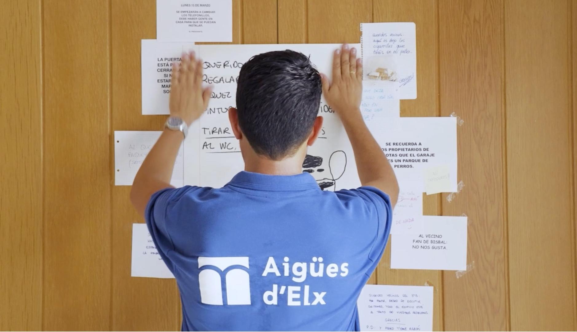 un hombre colgando un cartel en el tablón de anuncios del portal