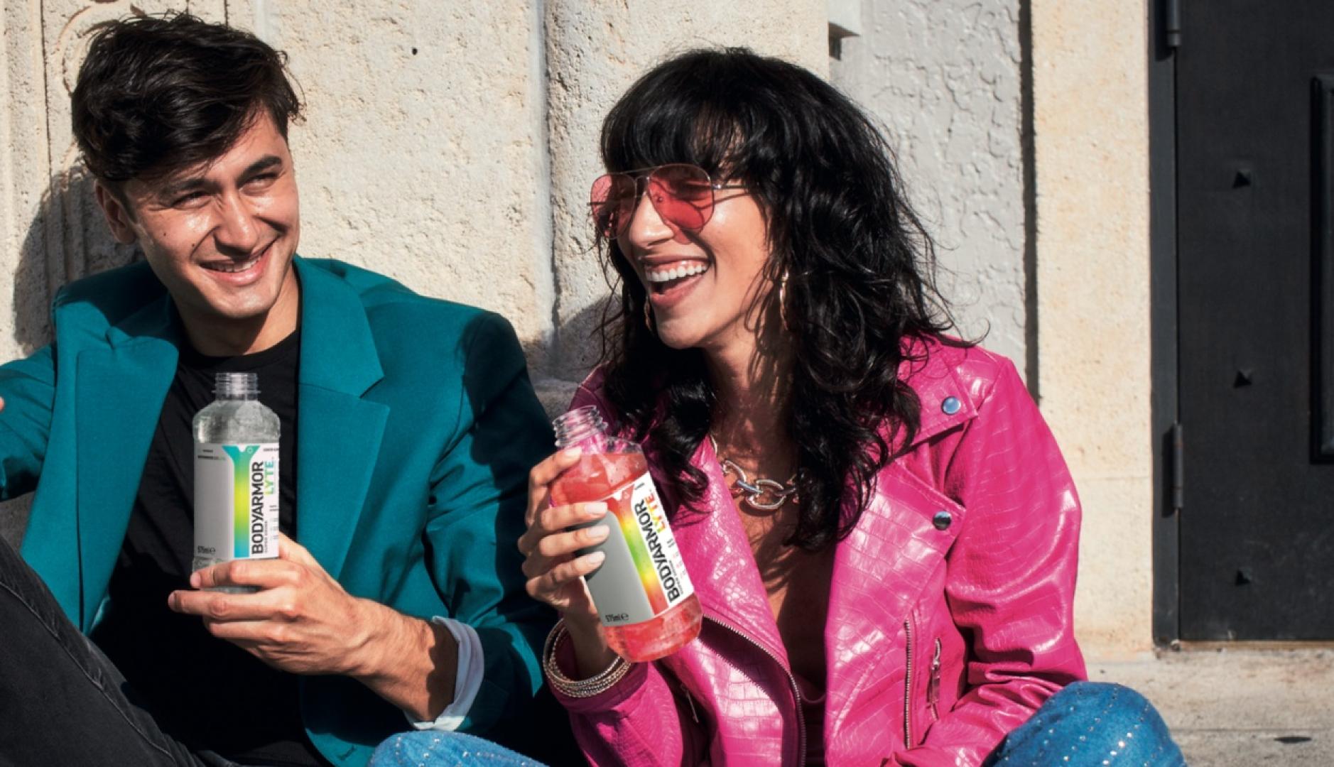 dos jóvenes sentados en el suelo, riendo con el producto en la mano