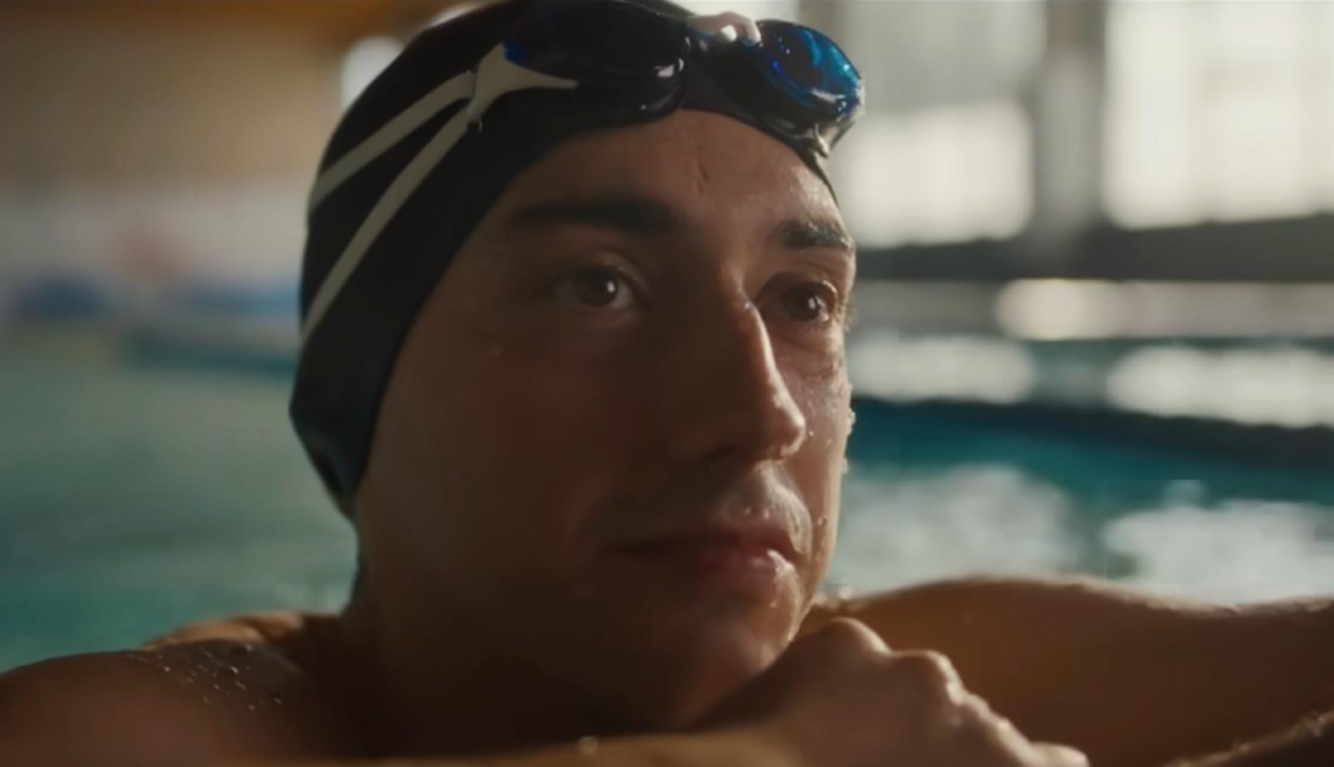 Primer plano de un chico apoyado en el bordillo de una piscina