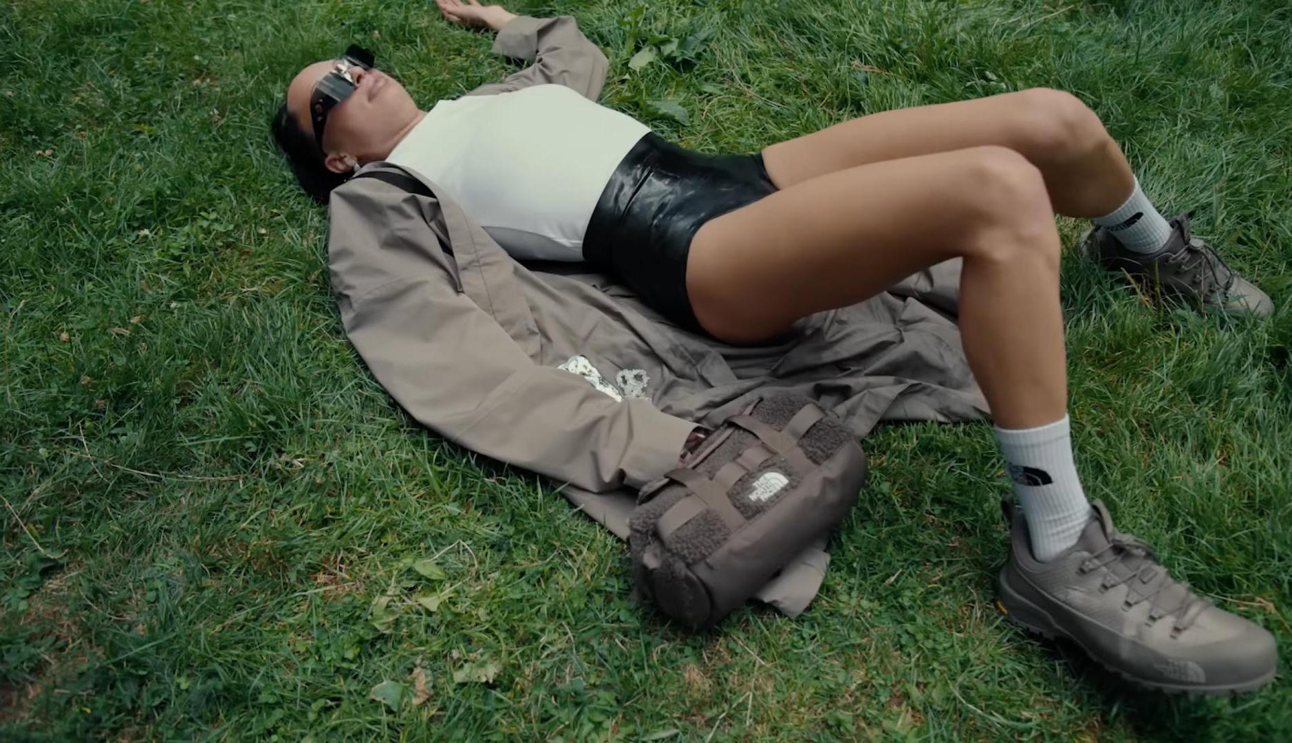 Chica vestida con ropa de The North Face tumbada sobre hierba