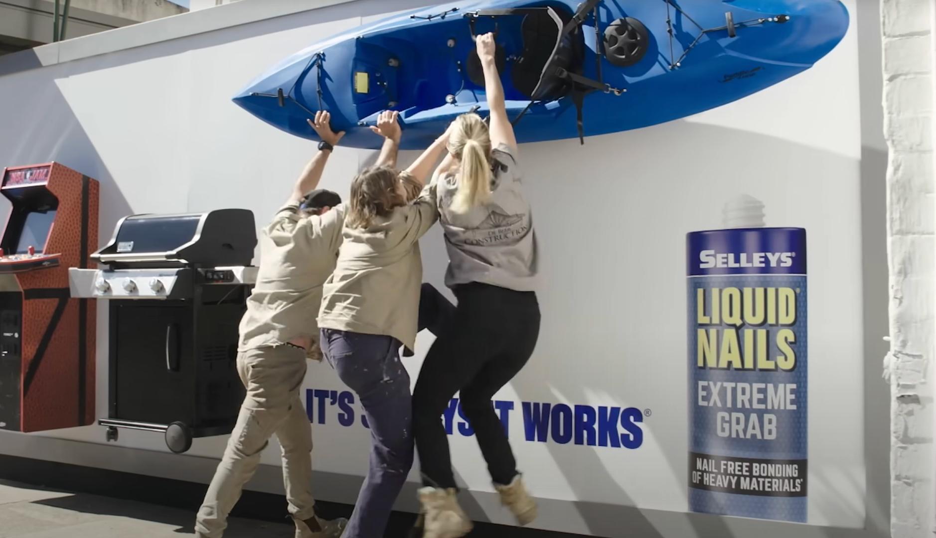 Tres personas intentando despegar un kayak de una pared