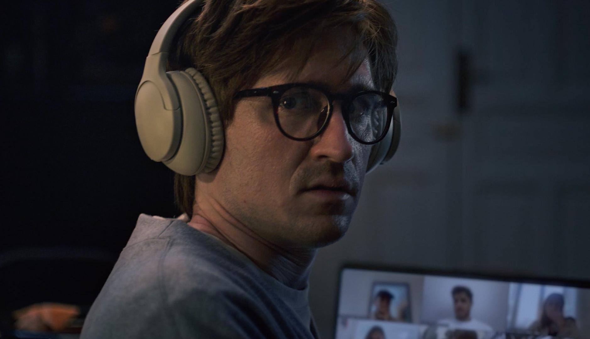 Chico con cascos haciendo una videollamada mirando con cara de susto