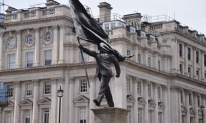 バンクシー作とされる、旗で目がくらみ棚から降りるスーツ姿の男性の新たな銅像がロンドン中心部に出現