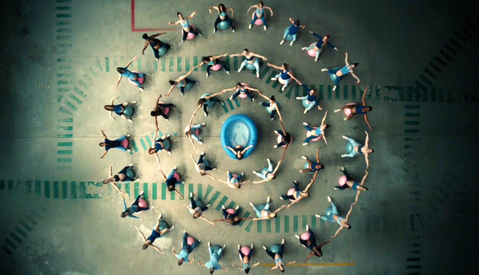 Un círculo de mujeres sobre pelotas de pilates alrededor de una piscina hinchable